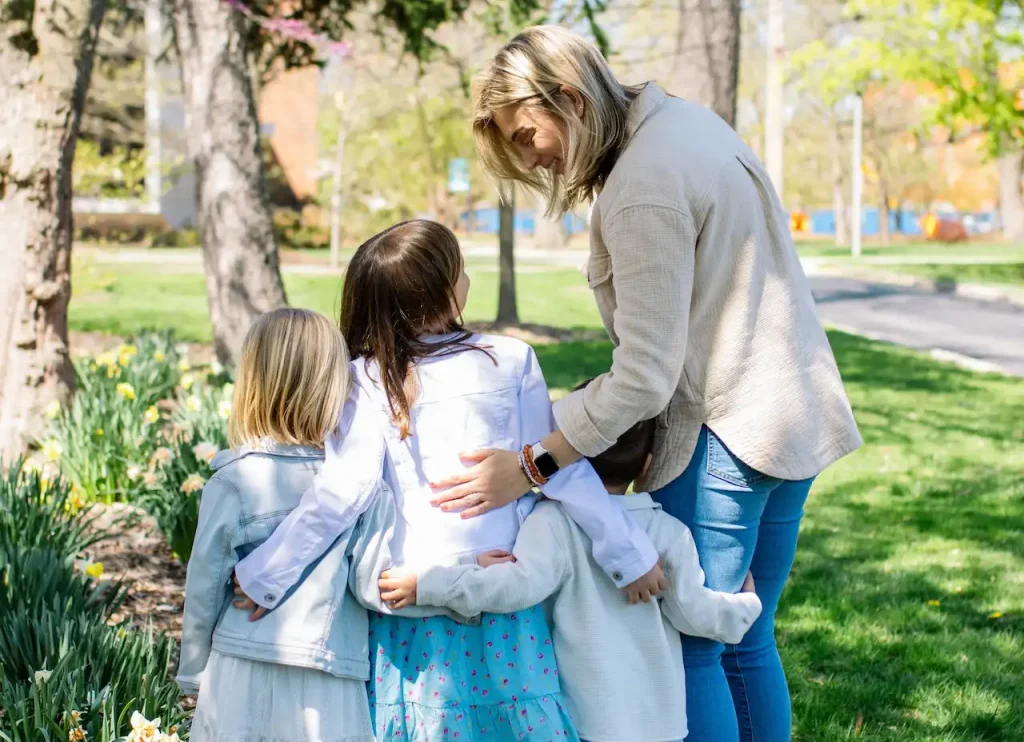 Woman hugging three children in park